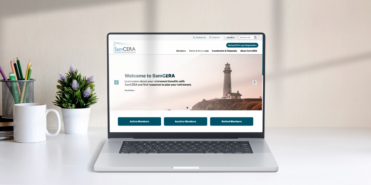 a laptop on a desk open to SamCERA's website with office supplies, a cup, and potted plant on the side